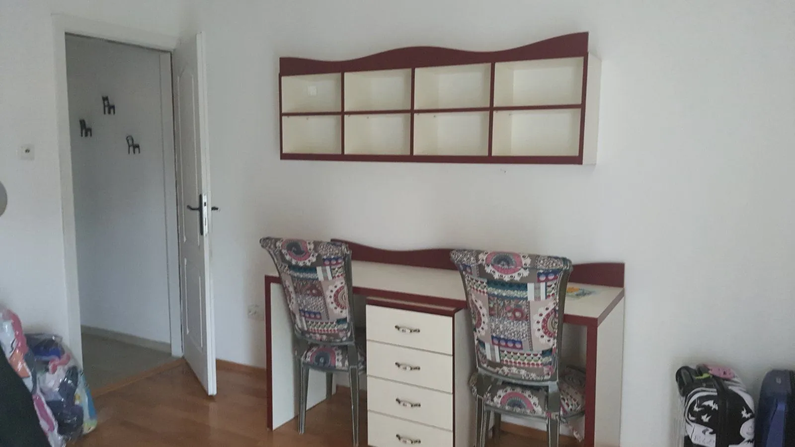 A study desk with two chairs and a wall shelf in a room.