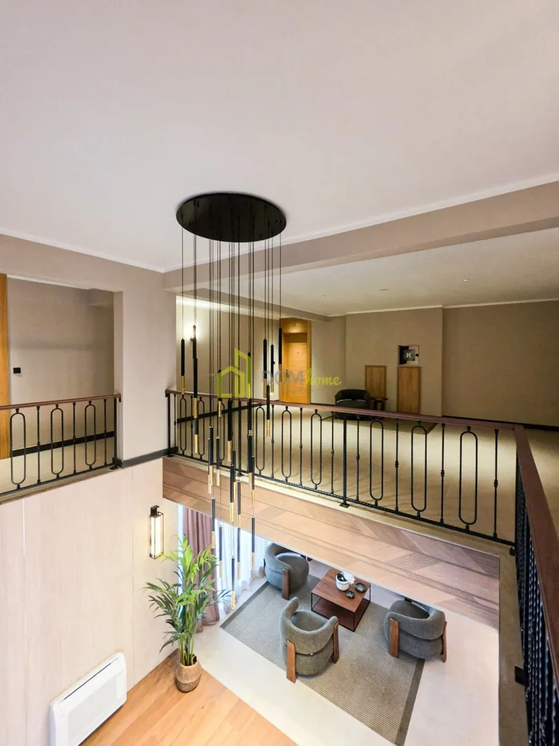 View from the gallery overlooking the living room and modern staircase with a chandelier.