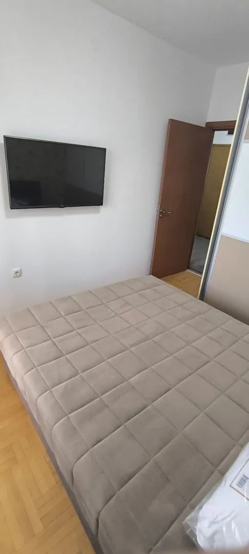 A simply furnished bedroom with a wall-mounted TV.