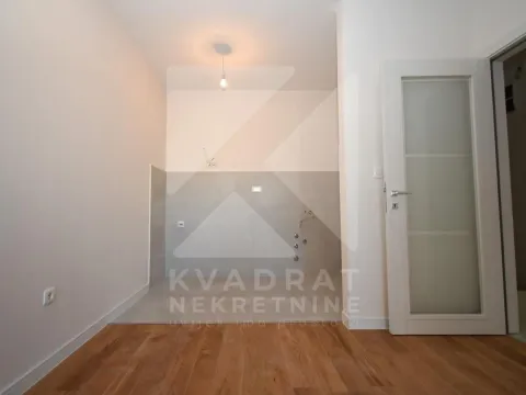 Prazna prostorija sa keramičkim pločicama na zidu i podu od parketa. - image 3