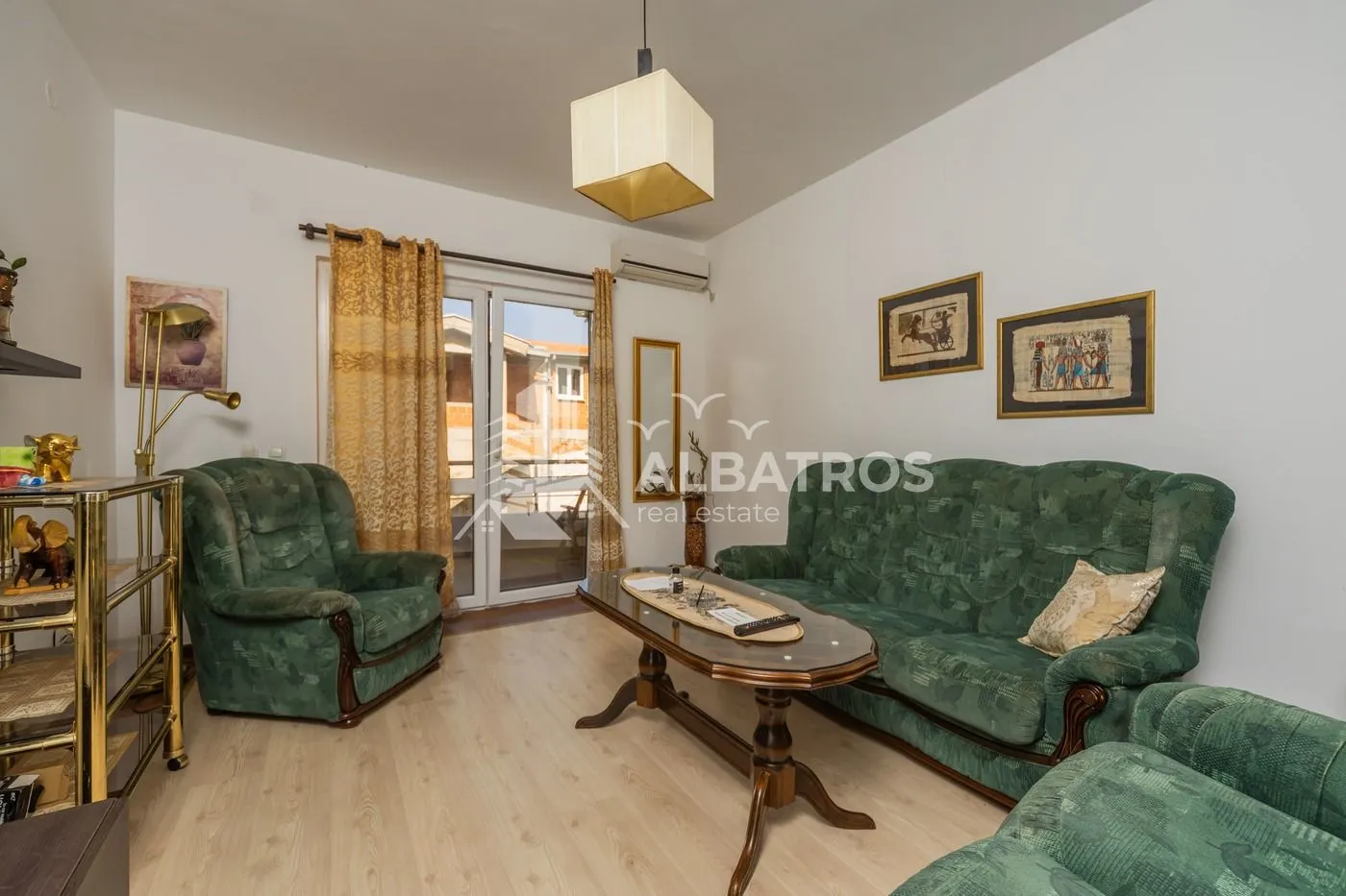 Living room with green seating furniture and access to the terrace.