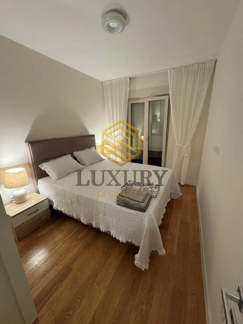 Bedroom with a double bed, nightstand, and balcony doors.