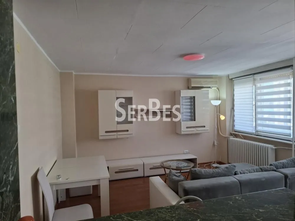 Dnevna soba sa garniturom, trpezarijskim stolom i montiranim elementima na zidu.