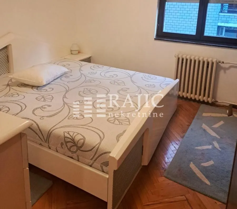 Furnished bedroom with a double bed and parquet flooring.