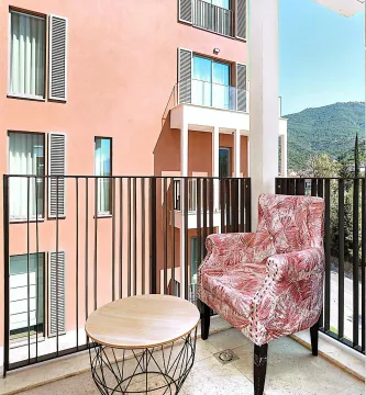 Natkriveni balkon sa foteljom, stočićem i pogledom na zgradu i brda. - image 7