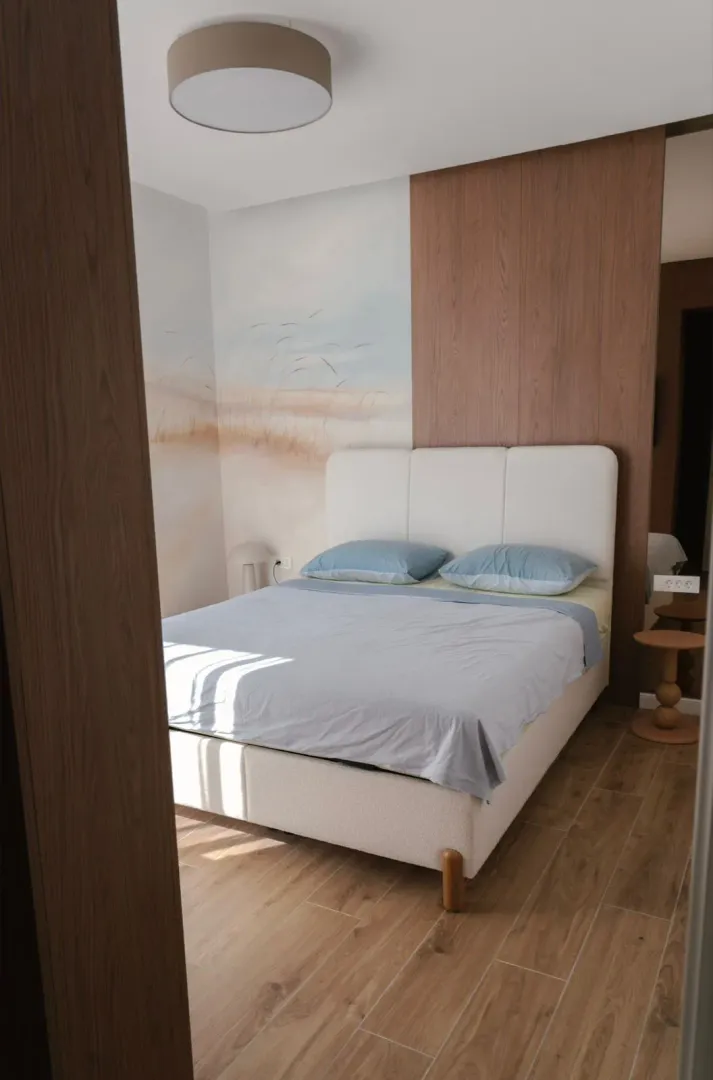 Modern bedroom with a double bed and wooden wall paneling.