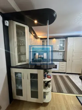 Kuhinja opremljena belim ormarićima, tamnom radnom površinom i šankom. - image 41