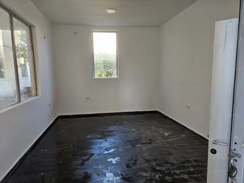Empty room with white walls and dark floor tiles. - image 2