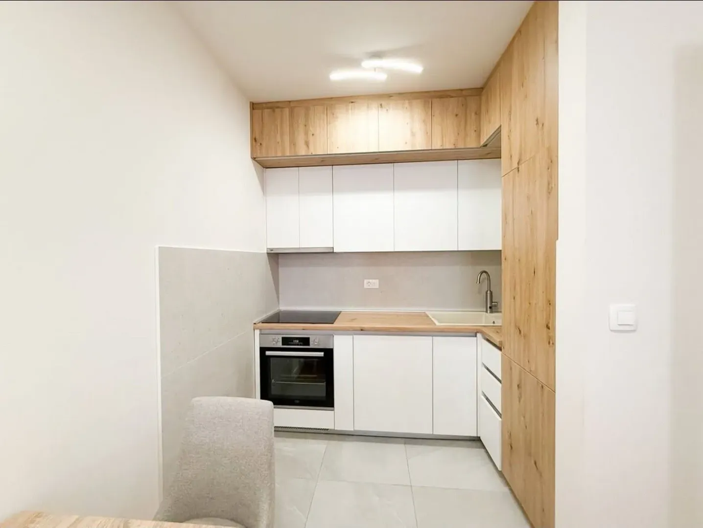 Modern white kitchen with wooden elements.