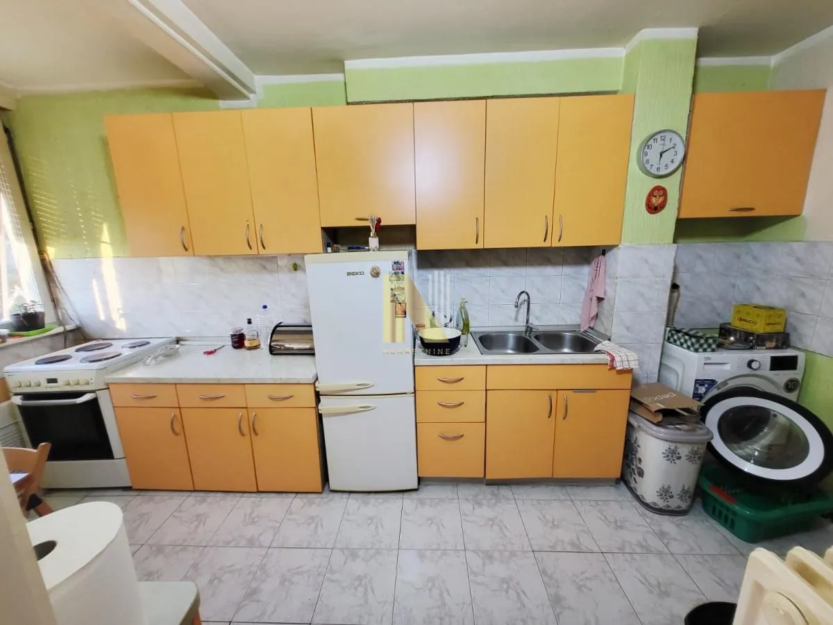 Manja kuhinja sa narandžastim elementima i osnovnim kućnim aparatima.