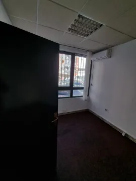 An empty room with a window, dark carpet, and an air conditioner. - image 9