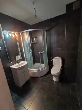 Kupatilo sa tamnim pločicama, tuš kabinom, umivaonikom i wc šoljom. - image 5
