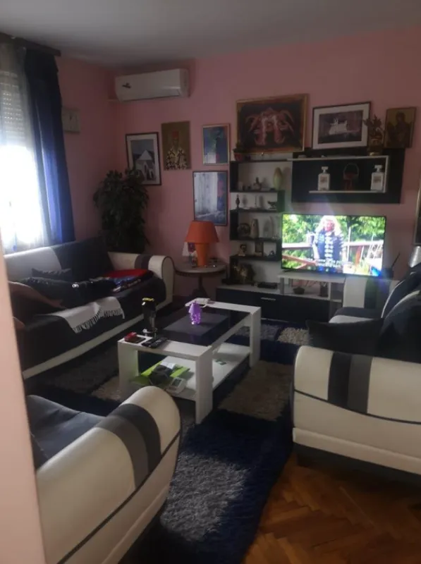 Dnevna soba sa garniturom za sjedenje, televizorom i pink zidovima.