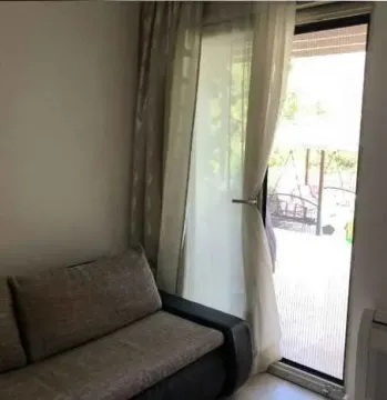 Dio dnevne sobe sa kaučem pored balkonskih vrata. - image 10