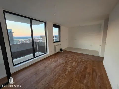 View of an unfurnished room with wooden flooring and a large window overlooking the city. - image 7