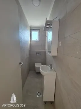 Small bathroom lined with grey tiles featuring a washbasin and a toilet. - image 17