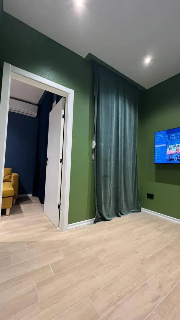 Moderna spavaća soba sa zelenim zidovima i drvenim podom.