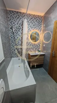 Moderno kupatilo opremljeno kadom, umivaonikom i ogledalom sa pozadinskim osvetljenjem. - image 11