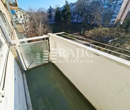 View from the balcony overlooking surrounding buildings and green area. - image 8