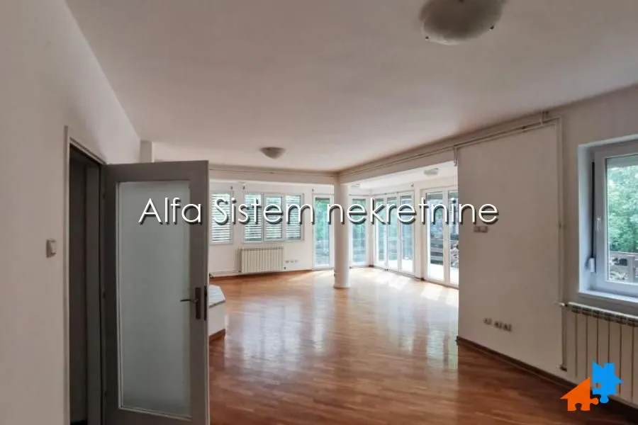 Spacious empty living room with parquet flooring and large windows.