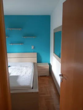 Svijetla spavaća soba sa plavim akcentnim zidom i drvenim krevetom. - image 14
