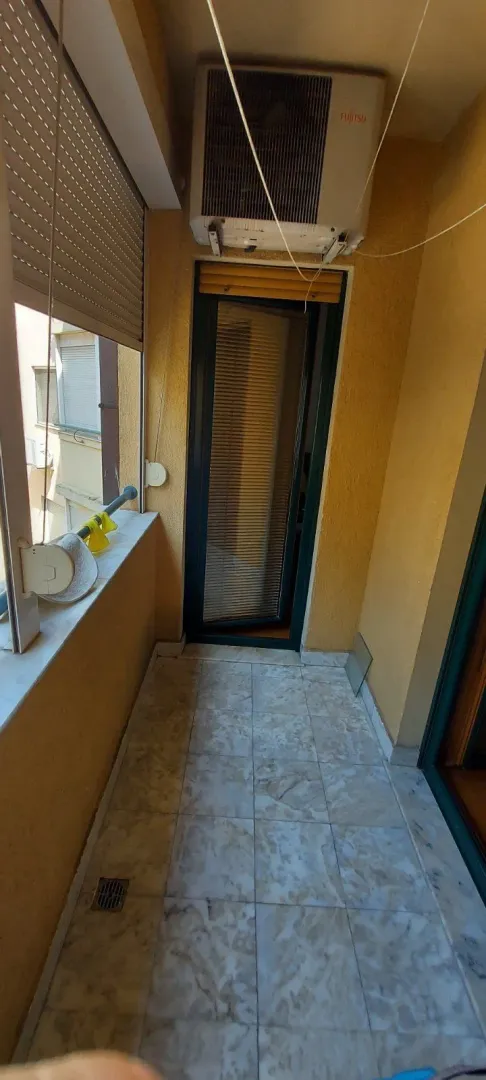 Uski balkon sa keramičkim pločicama i klima uređajem.