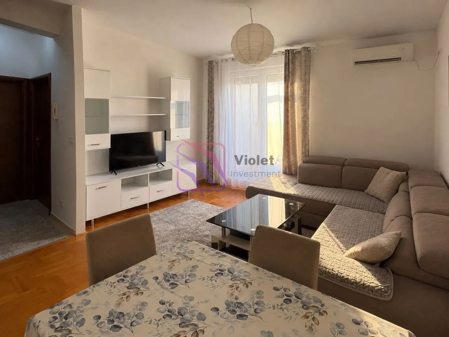 Living room with sofa, TV unit and dining table.