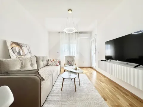 Dnevna soba sa garniturom, stočićima i televizorom na zidu. - image 2