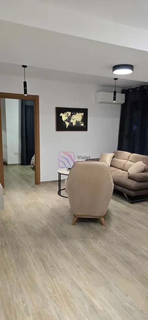 Dnevna soba sa garniturom, foteljom i staklenim stočićem.