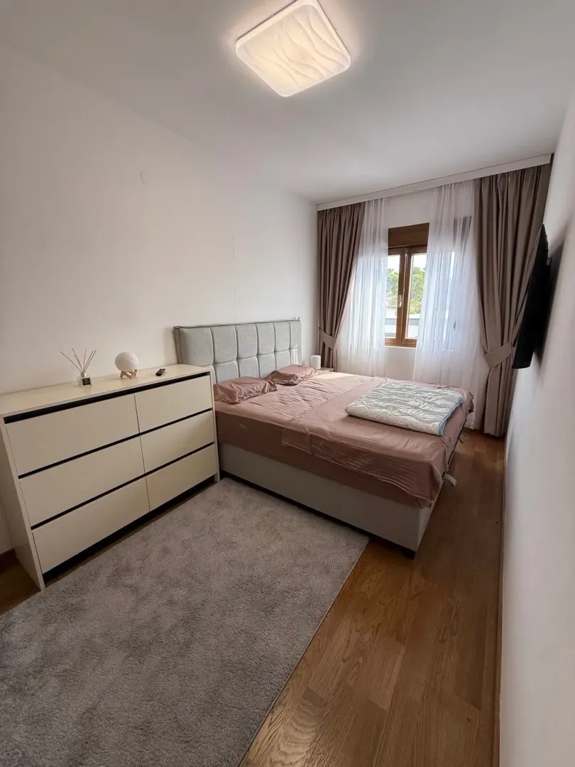 Svjetla i uredna spavaća soba sa bračnim krevetom i komodom.