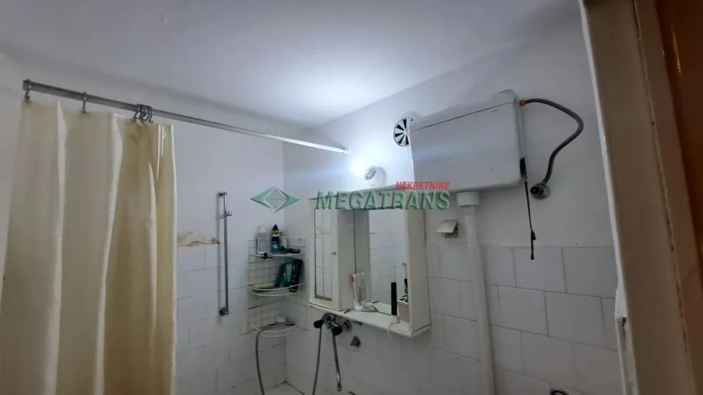 View of an older bathroom with white tiles and a shower curtain.