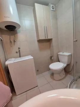 Small bathroom with a shower cabin, toilet, washing machine, and water heater. - image 8