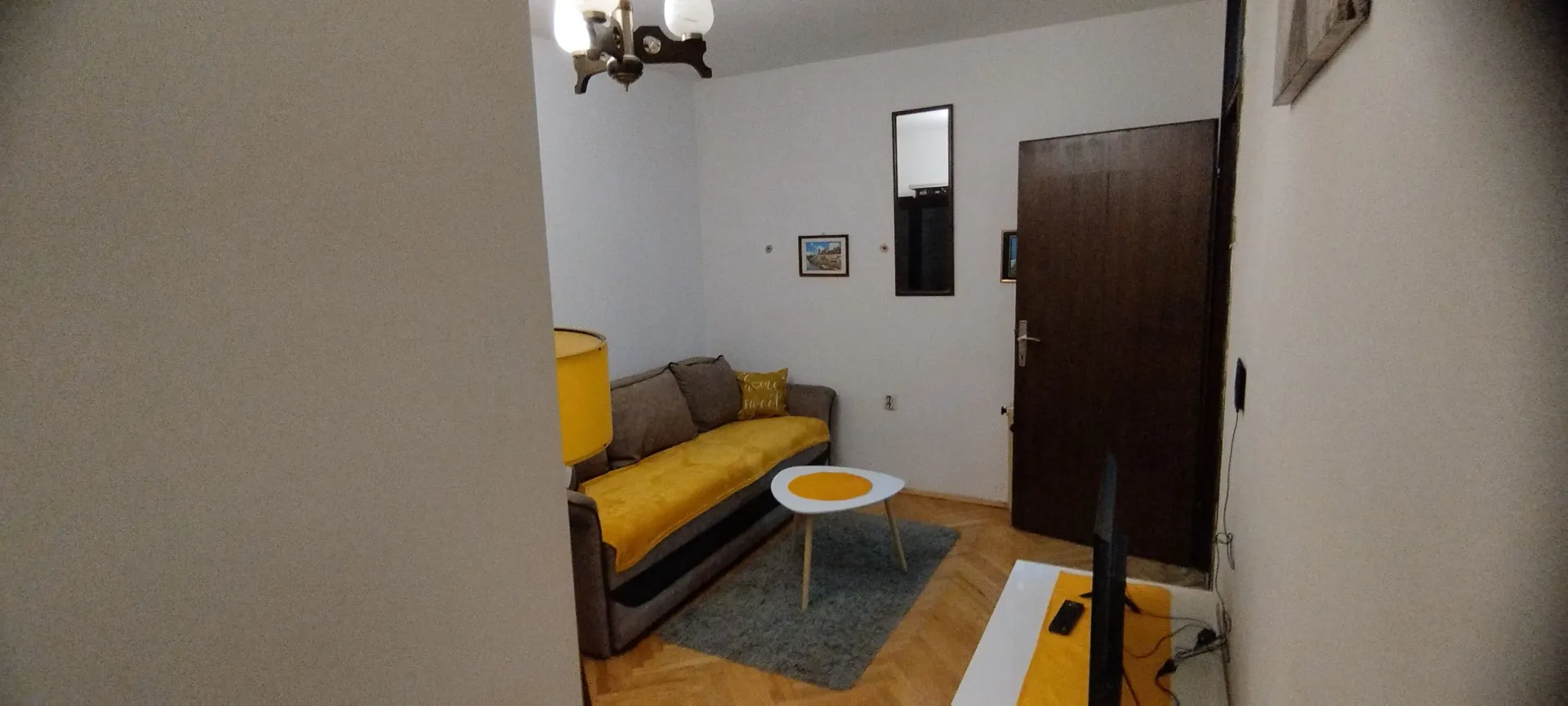 Manja dnevna soba sa garniturom, stočićem i televizorom.