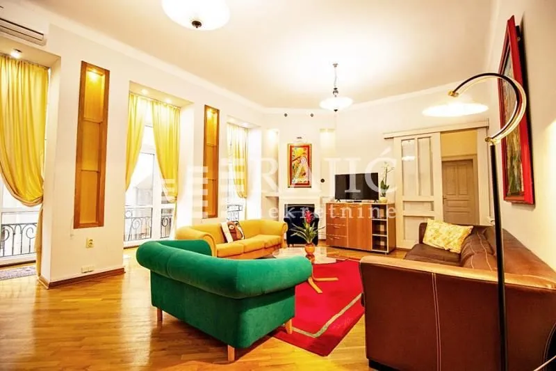 Spacious living room with seating furniture and parquet flooring.