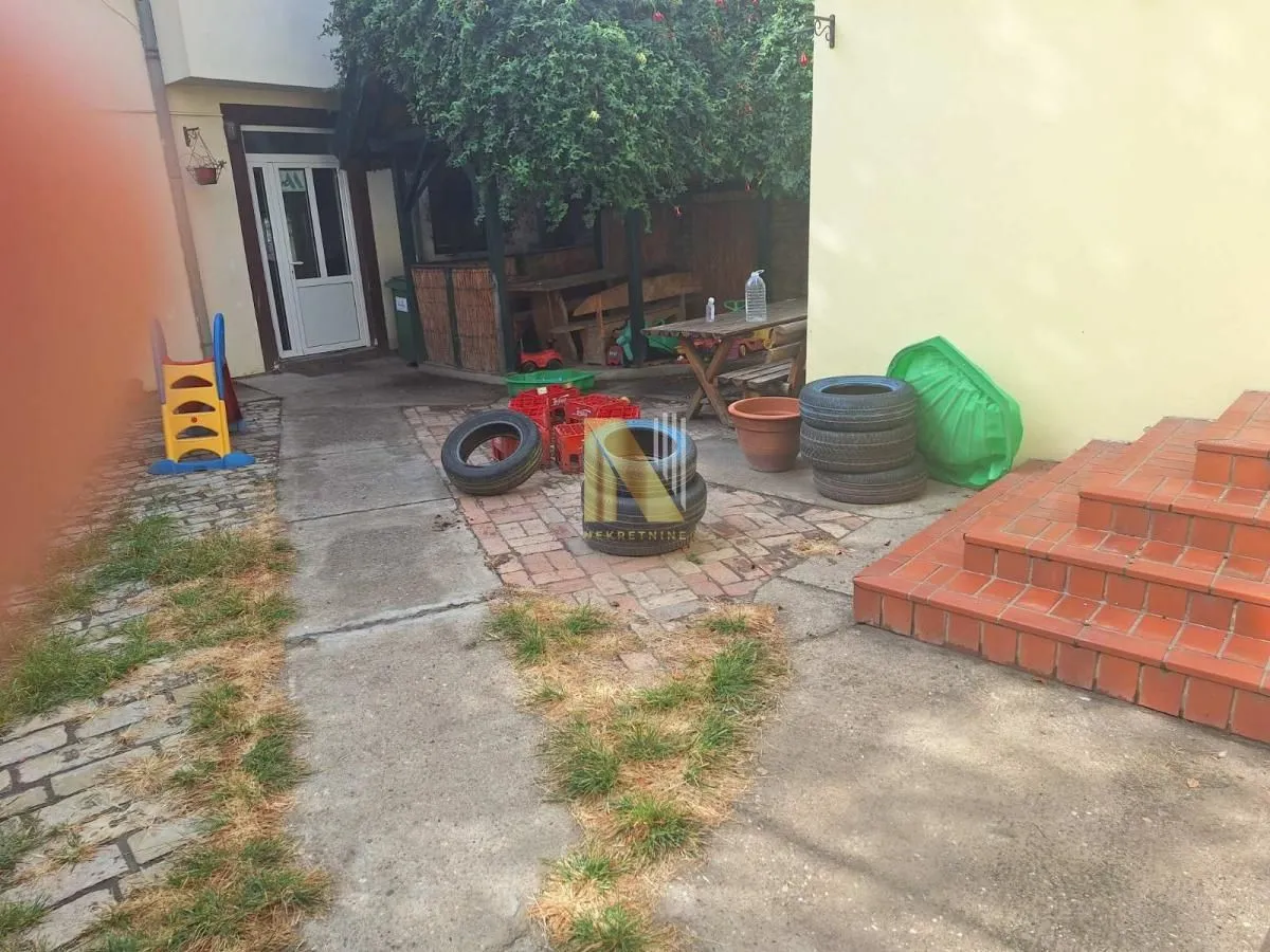 View of the paved yard with the entrance to the house and an outbuilding.