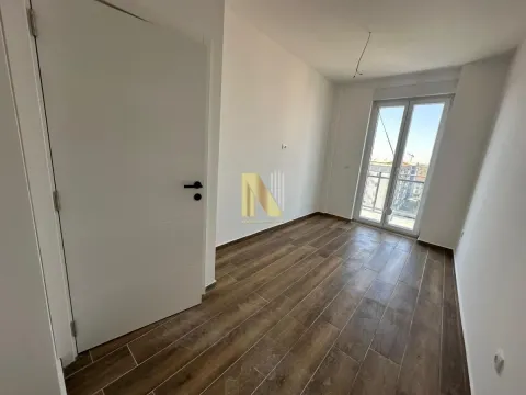 Prazna soba sa belim zidovima, drvenim podom i balkonskim vratima. - image 4