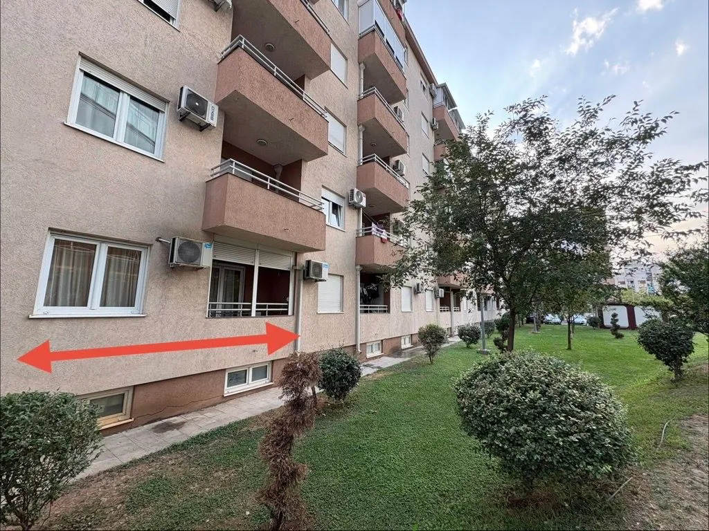 Pogled na spoljašnjost stambene zgrade sa uređenim dvorištem i travnjakom.