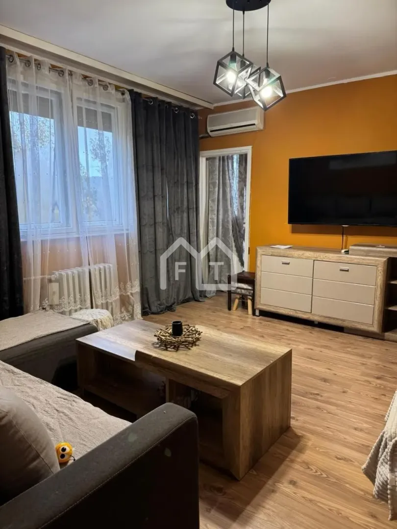 Living room with a sofa, wooden coffee table, TV and orange wall.