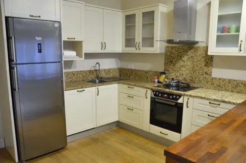 Kitchen with wooden cabinetry, refrigerator, and built-in oven. - image 11