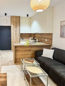Living room with a comfortable sofa and a kitchen in the background. - image 6