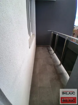 Nenameštena terasa sa tamnim pločicama i metalnom ogradom. - image 5