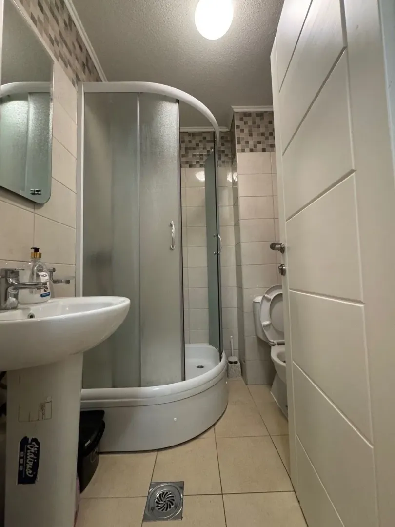 Smaller bathroom with a shower cabin, washbasin, and toilet.