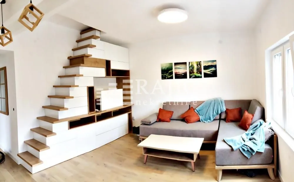 Living room with a sofa, coffee table, and stairs with built-in storage cabinets.