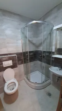 Small bathroom with a shower cabin, washbasin, and toilet. - image 6