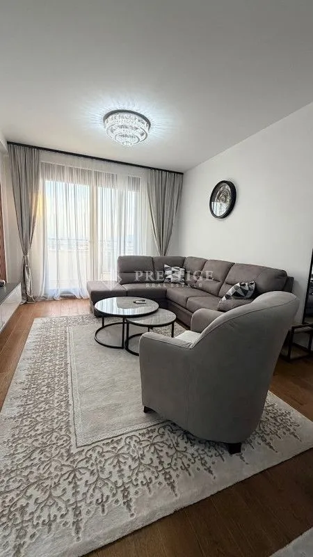 Spacious living room with a sectional sofa, armchair, and large balcony doors.