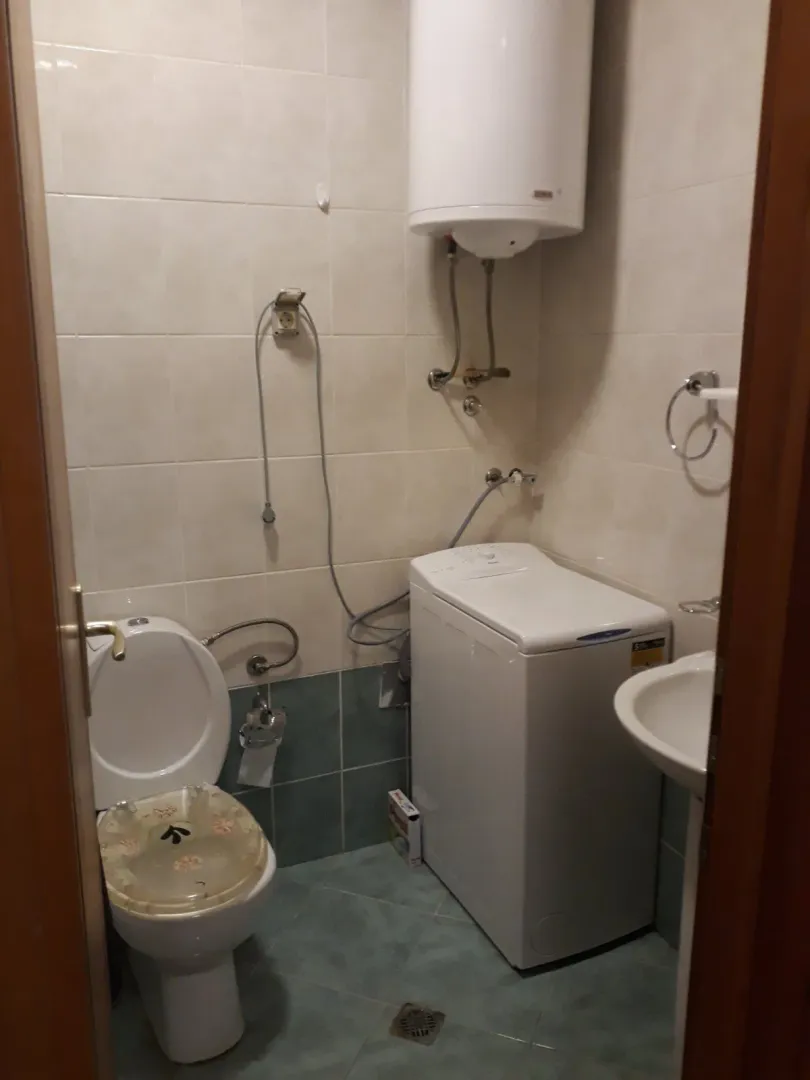 A simple bathroom featuring a toilet, washing machine, and water heater.