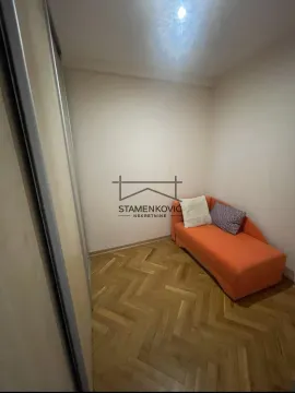 Manja spavaća soba sa narandžastim krevetom i parketom na podu. - image 8