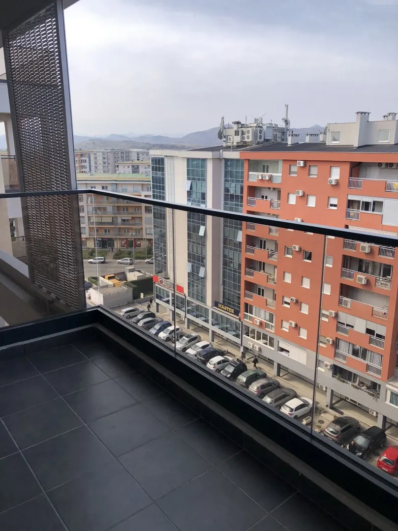 View from the balcony overlooking surrounding buildings and a parking lot.