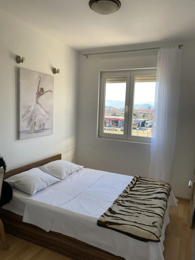Bright bedroom with a double bed and a view through the window.