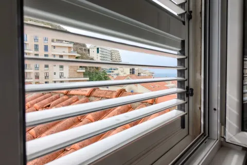 Pogled na grad i more kroz otvorene žaluzine sa prozora. - image 18